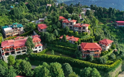 An aerial or drone view of the Leela Orchard property nestled amongst the trees with a view of the distant valley and mountains